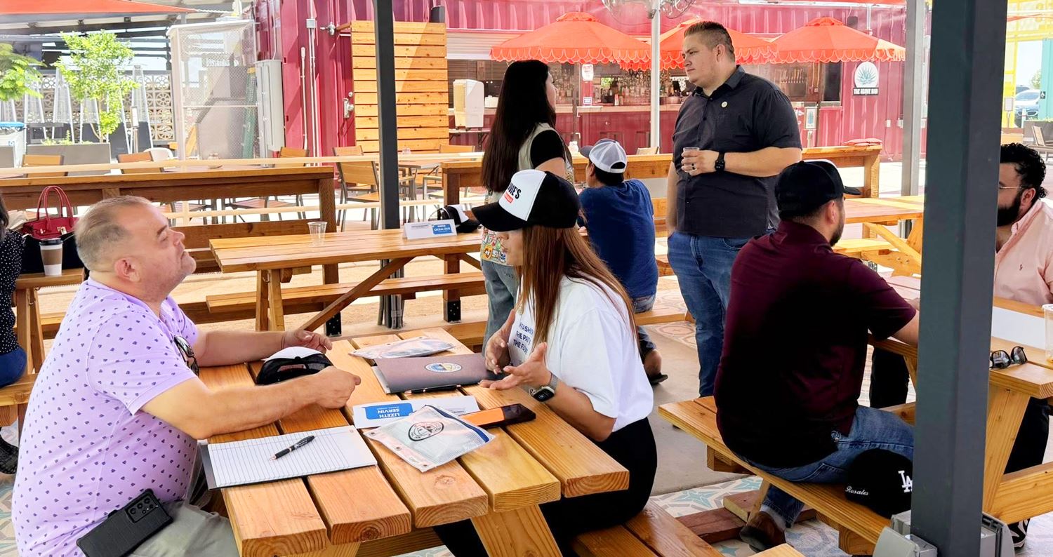 People dining at tables in an outdoor restaurant, enjoying their meals in a lively atmosphere.